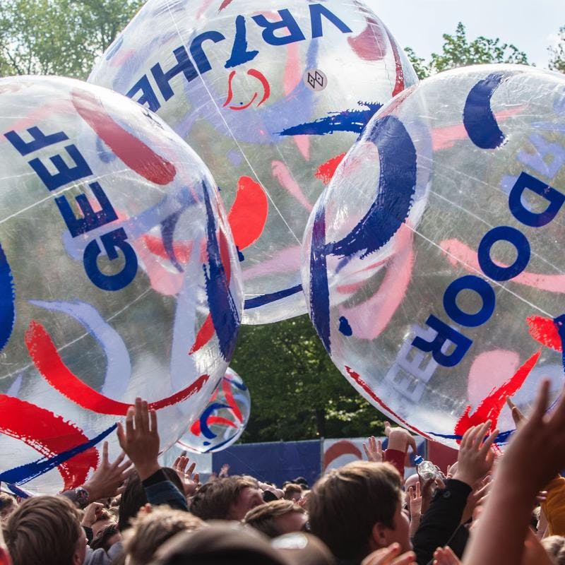 A photo of beach balls being thrown around by a lot of crowds at a festival